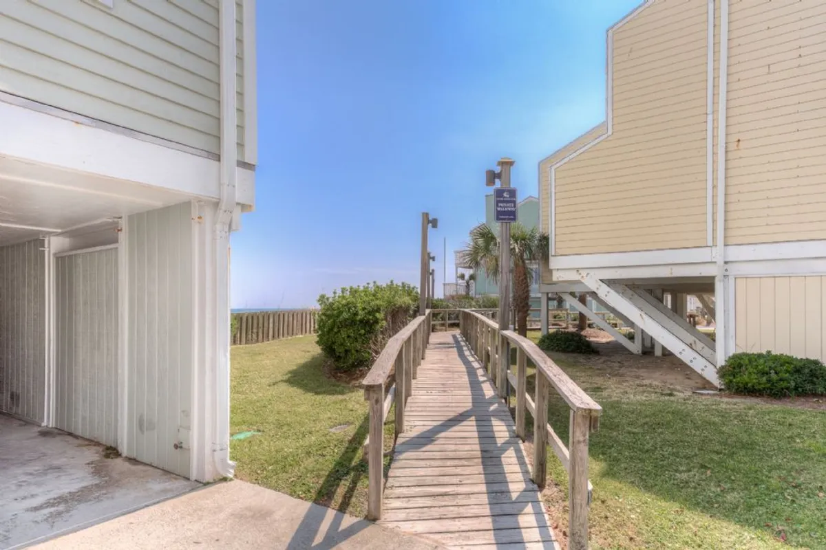 A tranquil exterior walkway lined with palm trees, leading toward the building and highlighting the inviting architecture. The scene suggests easy access to outdoor exploration and the beach, inviting guests to head out for walks, sightseeing, or outings to local parks and attractions.